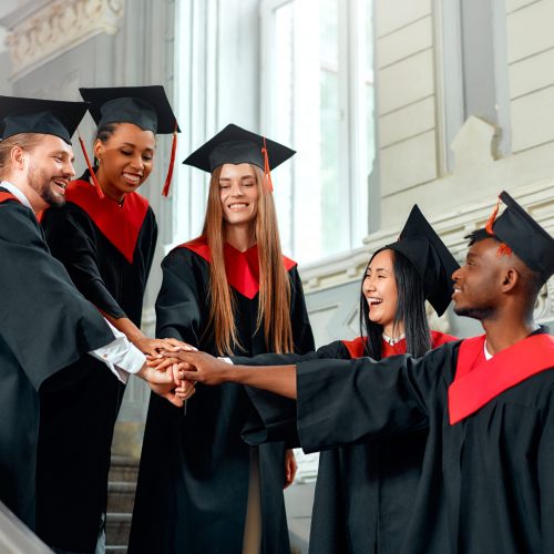 A diverse group of graduates in caps and gowns celebrate their achievement, sharing a joyful moment on a stairway. This marks a milestone in their education journey, symbolizing success and happiness